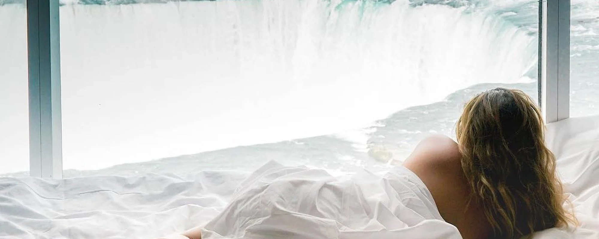woman in bed overlooking falls